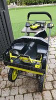 Front view of snow thrower housing, yellow intake auger and large treaded wheels