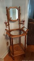 Frontal view of entire wash stand with mirror perched on two turned wood supports and two glass candle/oil holders attached.