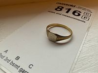 10k gold signet ring with engraved initials on a white display card, showing front and side view