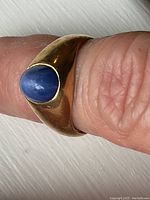 Front view of bezel-set oval blue stone on gold band