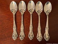 Five sterling silver teaspoons laid out in a row showing the bowl and handle decoration.