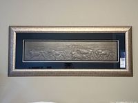 Front view of framed lion relief art piece showing the entire width and height with a silver metallic frame and dark matte.