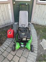 Front view of green and black Lawnboy lawn mower with fabric grass bag and 10L red jerrycan on left side.