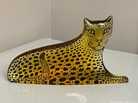 Front profile view showing stylized yellow and black spotted leopard motif on lucite base