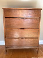 Front view showing four drawers and integrated carved finger-pull handles