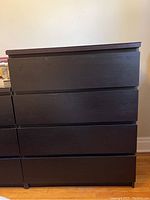 Front view of the black dresser showing four drawers and the flat top surface.