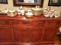Wide view of entire set displayed on sideboard showing stacks of plates, cups, teapot, creamer, and sugar bowl.