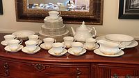 Front view of all china pieces displayed on sideboard showing stacked plates, cups, saucers, teapot, gravy boat and serving pieces