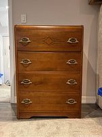 Full front view of the vintage solid wood highboy dresser showing four drawers and decorative brass handles.