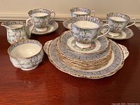 Full overview of the tea set showing cups, saucers, plates, creamer and sugar bowl with the Silver Birch pattern and gold edges.