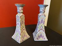 Pair of antique hand painted candelabras photographed front angle showing detailed floral leafy design.