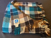 Folded Canadian tartan wool nylon blend blanket showing label and fringed edges
