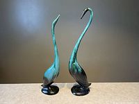 Pair of tall Blue Mountain Pottery swan figurines standing side by side with turquoise and black finish.