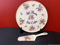 Front view of the ceramic cake plate and server displayed on the stand against a red background.