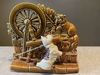 Front angled view showing dog pulling on rope and cat sitting on a wheel next to foliage with plant compartments behind.