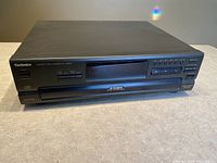 Black Technics SLPD665 compact disc changer on countertop with front view showing buttons, display, and branding.