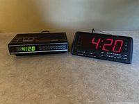 Two older clock radios side by side on a counter, showing time 4:20; one with red digital display, other with green.