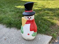 Front view of the vintage blow mold snowman on a concrete surface with grass background