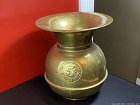 Side view of vintage brass spittoon showing embossed 5c Cigars All Famous Havana design on body.
