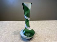 Front view of the vintage green and white swirl glass bud vase showing tall slender shape and swirl design.