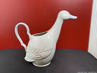 Photo of the white ceramic goose-shaped vintage pitcher, showing side profile with handle and spout detail