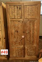 Front view of full armoire showing six carved floral panel doors and overall proportions