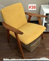 Three-quarter view of teak armchair showing frame, armrests, upholstery and leg profile