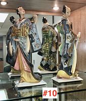 Front view of both figurines on glass shelf showing samurai and female figure