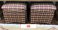 Pair of ottomans shown side-by-side beneath a console table on a floral rug, highlighting plaid pattern and fabric upholstery.