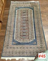 Full view of carpet laid flat on hardwood floor showing central medallion and border design