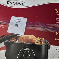 Photo of the roaster oven in its retail box showing front of the box and part of the oven with control dial and cooked food image.