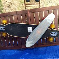 Top view of the 38-inch long board skateboard with black grip and yellow wheels on wooden surface