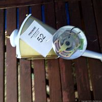 White exterior light fixture with mounting base and wiring exposed, placed on wooden surface.