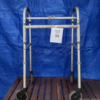 Front view of a foldable assistive walker with height adjustment holes on legs and two front wheels.