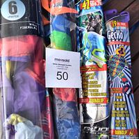 Photo showing kite packaging including a 6-foot nylon and fiberglass stunt kite, and packaging for a small gecko kite with colorful design and branding visible.