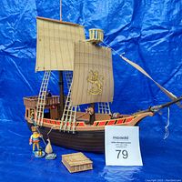Wide shot of Playmobil pirate ship with sails, king figure, and various accessories on blue backdrop