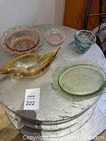 Overview of all five glass decorative pieces on a round wooden table, showing rose, green, orange, and blue colored glass items.