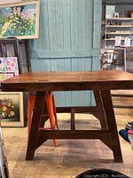 Side view showing the thick wooden tabletop with a warm natural finish and the robust wooden legs forming an A-frame design.