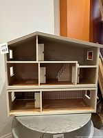 Front view of the three-level wooden doll house showing internal doors and stair details