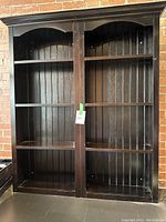 Full front view of the two bookshelves joined together, showcasing the dark wood finish and vertical panel backing.