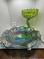 Green carnival glass pedestal compote bowl with scalloped rim and twisted stem paired with one iridescent ruffled edge bowl.
