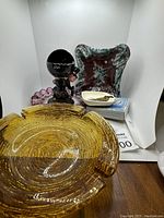 Photo shows various ashtrays including large yellow glass, large maroon/green ceramic, and purple glass small ashtrays.