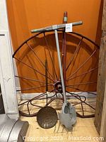 Overview of vintage wagon wheel leaning against wall with tools displayed around it.