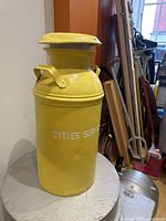 Front side view of yellow metal milk can labeled 'CITIES SERVICE'.