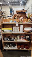 Full view of three shelves with small ceramic decor, kitchen items, steins, sad irons, and various decorative objects.