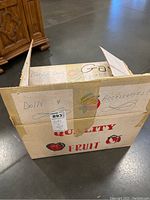 Cardboard box labeled for dolls and accessories on a concrete floor