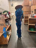 Full length photo of the hanging lamp with blue glass discs showing length and density of discs, hanging from ceiling.