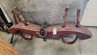 Overall view of the wooden ox yoke showing the full length with two upright wooden pegs and attached metal rings.