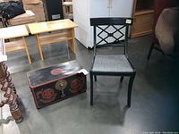 Shows black side chair with gray fabric seat beside black and red Chinese chest with brass toned hardware, illustrating lot contents
