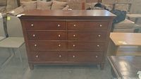 Front view of brown wooden dresser with eight drawers and silver knobs.